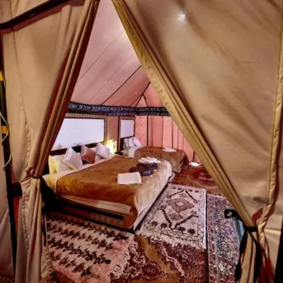 a bedroom with two beds in a tent at Luxury Sahara Camp in Merzouga