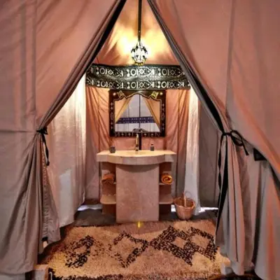 a bathroom with a sink and a mirror in a tent at Luxury Sahara Camp in Merzouga