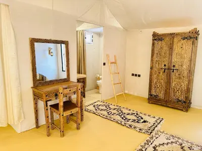 a room with a mirror and a dressing table and a door at Luxury Sahara Camp in Merzouga