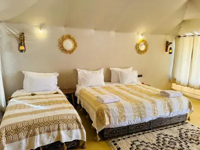 a bedroom with two beds and two mirrors on the wall at Luxury Sahara Camp in Merzouga