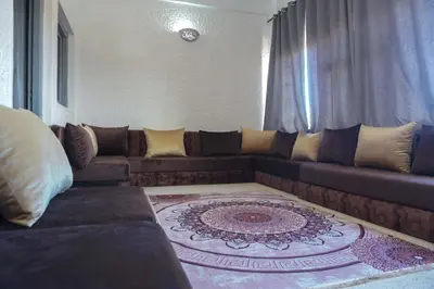 a living room with a brown couch and a rug at Hotel Warda in Ouarzazate