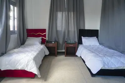 a bedroom with two beds and two night stands at Hotel Warda in Ouarzazate