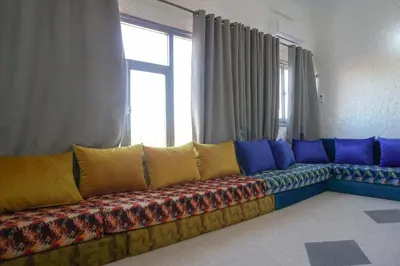 a couch with colorful pillows in a room with a window at Hotel Warda in Ouarzazate