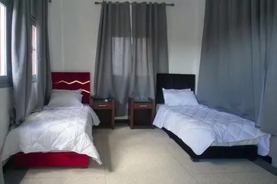 a bedroom with two beds and two windows at Hotel Warda in Ouarzazate