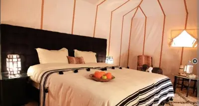 a bedroom with a bed with a bowl of fruit on it at Merzouga bivouac star in Taouz