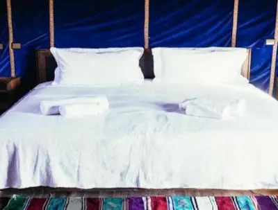a white bed with two towels on top of it at Merzouga bivouac star in Taouz