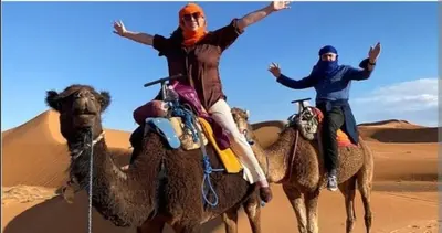 two men riding on the backs of camels in the desert at Merzouga bivouac star in Taouz