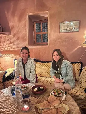 two women sitting at a table with plates of food at Kasbah Tigmi El Janoub in Aït Ben Haddou