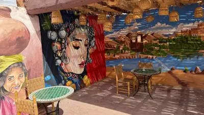 a room with tables and chairs and a mural at Kasbah Tigmi El Janoub in Aït Ben Haddou