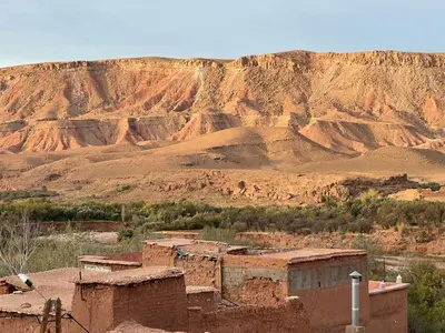 a village in the desert with a mountain in the background at Kasbah Tigmi El Janoub in Aït Ben Haddou