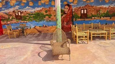 a room with chairs and a wall with a mural at Kasbah Tigmi El Janoub in Aït Ben Haddou
