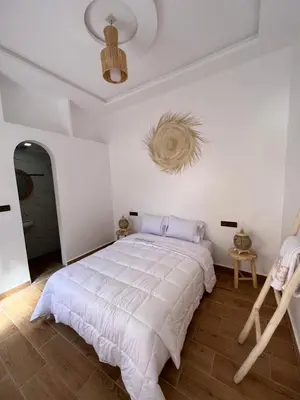 a white bedroom with a large bed and a ceiling at Rose Garden Dades in Iqouassene