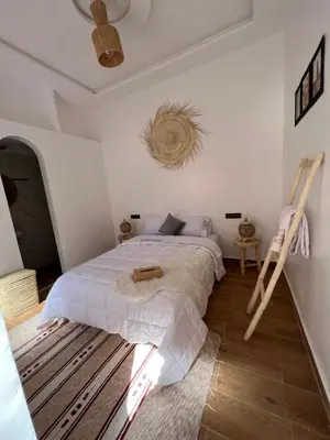 a bedroom with a bed and a wooden floor at Rose Garden Dades in Iqouassene