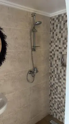a shower in a bathroom with a tile wall at Rose Garden Dades in Iqouassene