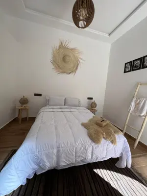 a bedroom with a white bed with a brown blanket at Rose Garden Dades in Iqouassene