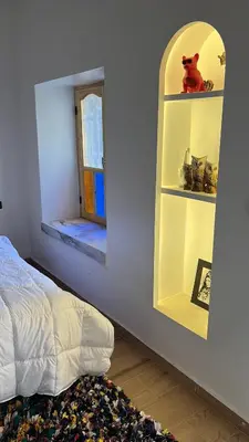 a bedroom with a bed and a shelf with a window at Rose Garden Dades in Iqouassene