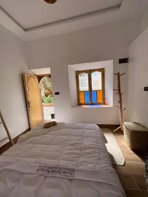 a bedroom with a large bed and two windows at Rose Garden Dades in Iqouassene