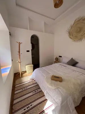 a bedroom with a bed and a cross on the wall at Rose Garden Dades in Iqouassene