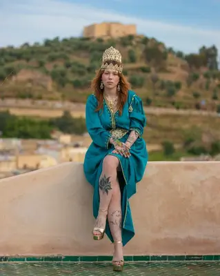 a woman in a blue dress sitting on a wall at Dar Usham Fes Luxury Guest House in Fès