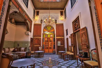 a large room with a chandelier and tables and chairs at Dar Usham Fes Luxury Guest House in Fès