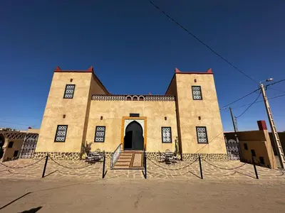 a large brick building with a door in the middle at Dar Hassan Merzouga in Merzouga