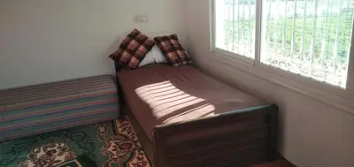 a small bed in a corner of a room with a window at DAR RACHIDA in Aït Taoujdate