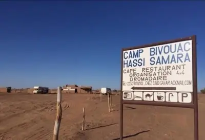 a sign in the middle of a dirt field at Camp Bivouac Hassi Smara in Tâlhâ