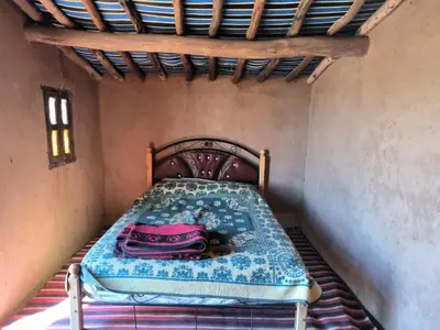 a small bed in a small room with a pink purse on it at Camp Bivouac Hassi Smara in Tâlhâ