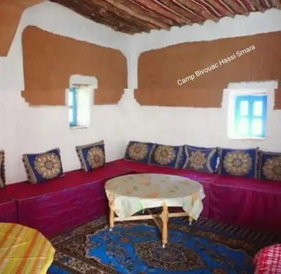 a living room with a red couch and a table at Camp Bivouac Hassi Smara in Tâlhâ