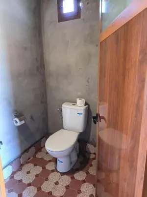 a bathroom with a toilet and a window and a door at Camp Bivouac Hassi Smara in Tâlhâ