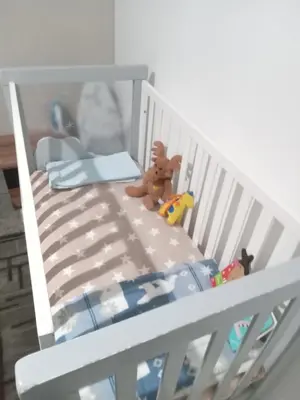 a white crib with a teddy bear and toys on it at Chez Siham in Fès