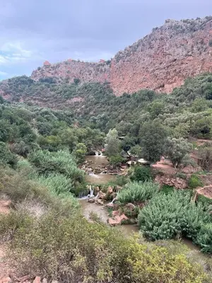 a river in the middle of a valley with a mountain at Ighbola Ouzoud in Ouzoud