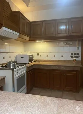 a kitchen with wooden cabinets and a stove top oven at Villa jouhara in Ifrane