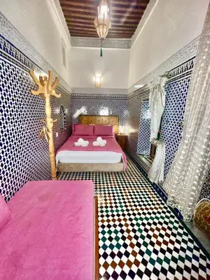 a bedroom with a pink bed with a cross on it at Riad Dar Lalj Fes in Fès