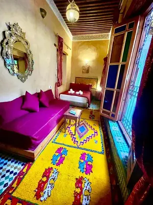 a living room with a purple couch and a colorful rug at Riad Dar Lalj Fes in Fès