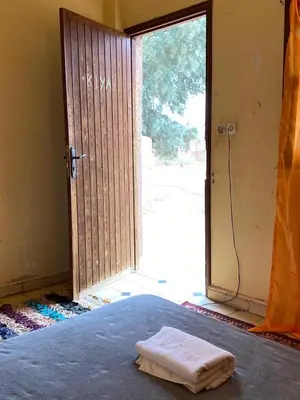 an open door to a room with a bed and a window at La Maison-Berbère Mhamid in Mhamid