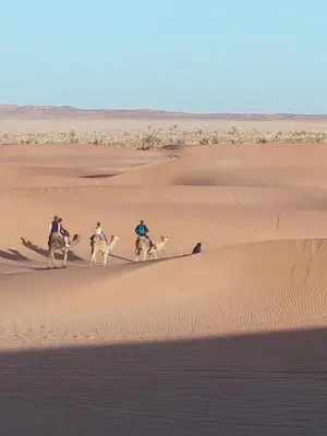 a group of people riding horses in the desert at La Maison-Berbère Mhamid in Mhamid