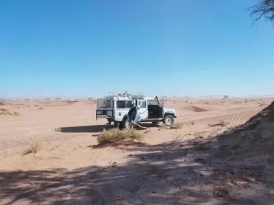 a jeep parked in the sand in the desert at La Maison-Berbère Mhamid in Mhamid