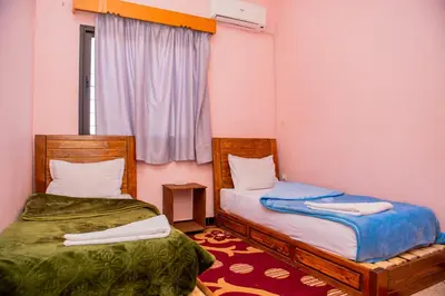 two beds in a small room with a window at résidence afgo Ouarzazate in Ouarzazate