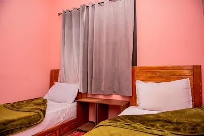 two beds in a room with pink walls and curtains at résidence afgo Ouarzazate in Ouarzazate