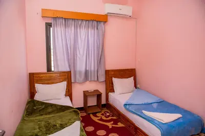 two beds in a small room with a window at résidence afgo Ouarzazate in Ouarzazate