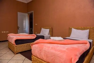 a room with three beds with orange sheets at résidence afgo Ouarzazate in Ouarzazate