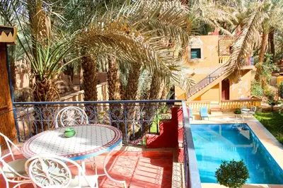 a balcony with a table and chairs and a pool at Riad Soleil du Monde in Zagora