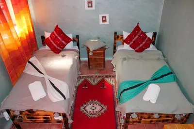 two beds with red pillows on them in a room at Riad Soleil du Monde in Zagora