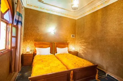 a bedroom with a large yellow bed with two pillows at Riad Soleil du Monde in Zagora