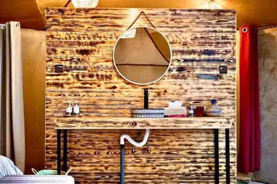 a bathroom vanity with a mirror on a wooden wall at Sky View Camp in Merzouga