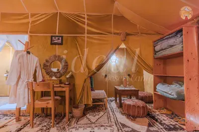 a bedroom with a tent with a desk and a table at ideal desert camp in Merzouga