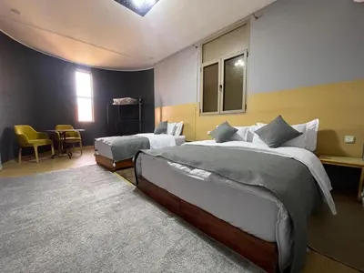 a bedroom with two beds and a table and chairs at Palm Garden in Erfoud