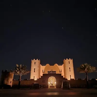 a building lit up at night with cars parked in front at Palm Garden in Erfoud