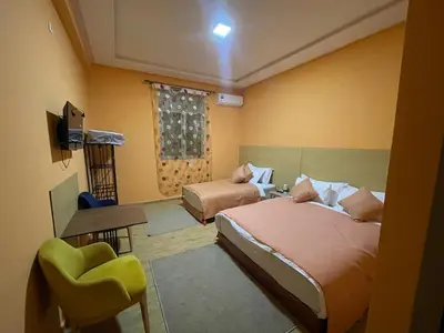 a bedroom with two beds and a chair and a television at Palm Garden in Erfoud
